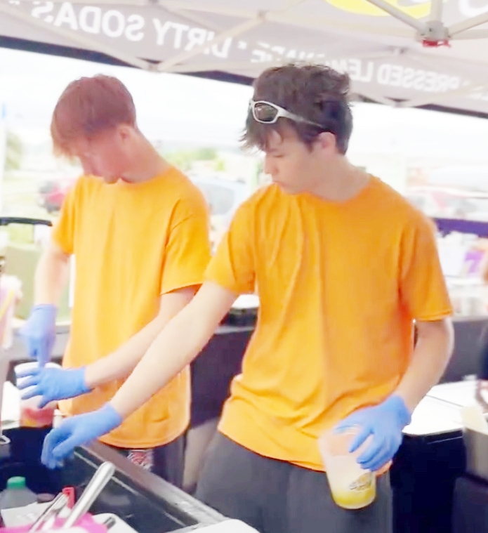 Charlie Keller (right) running Charlie’s Lemonade, now with a custom 10x15’ tent and a thriving team.