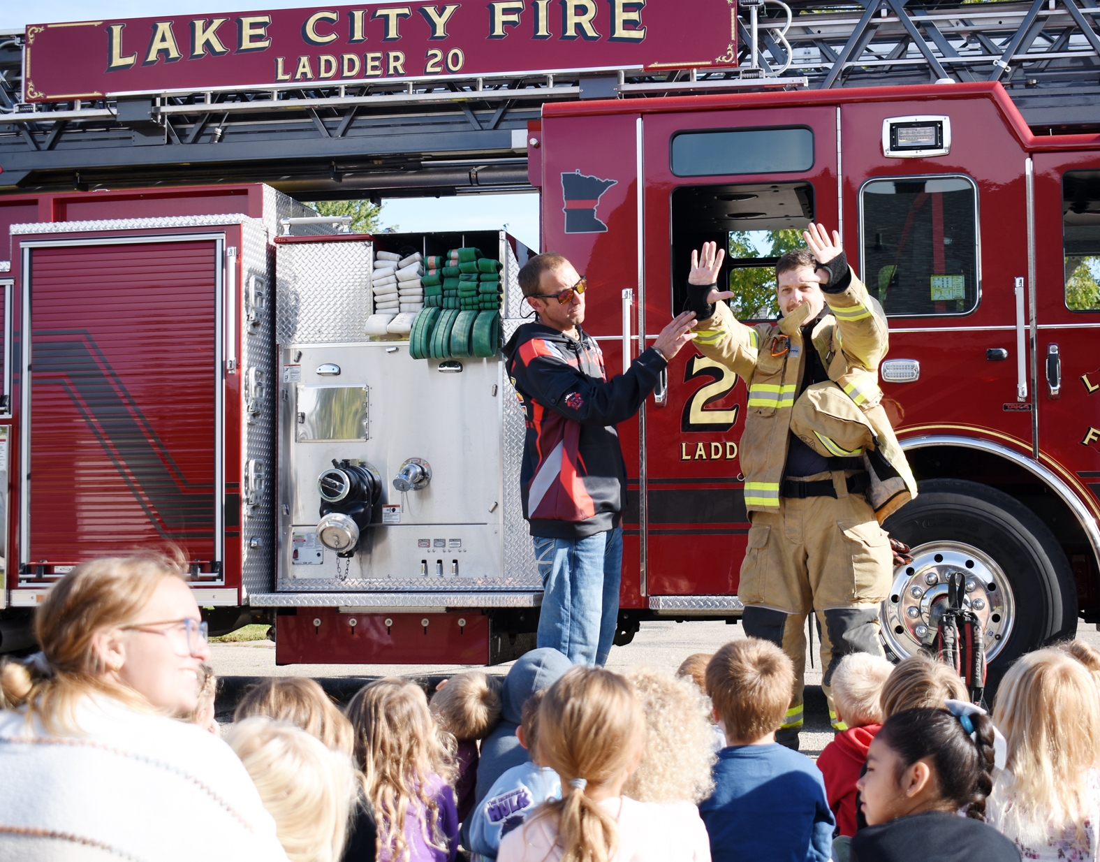 Speaking to students at St. John’s Lutheran School Oct. 8, Lake City Firefighters Michael Lafferty (left) and Casey Henderson explain how firefighters’ turnout gear protects them while fighting fires.